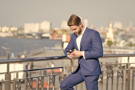 Businessman with smartphone on terrace on cityscape, business communication. Man in business suit with mobile phone, new technology. Business communication, new technology, sms. Modern life, lifestyleの写真素材