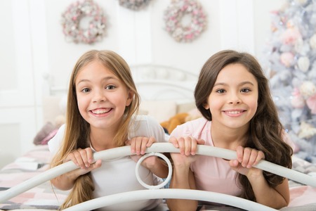 Time to share all the laughter and joy. Happy children have Christmas spirit. Small girls in bed on Christmas eve. Small children in bedroom with Christmas tree. Childhood Christmas traditions.の写真素材