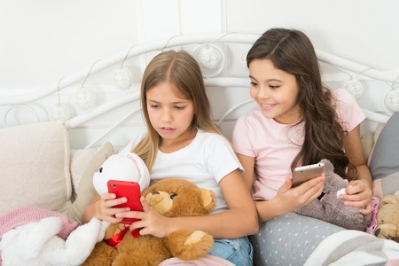 Well, you only look. Ordering gifts for Christmas and New Year by phone. Little girls use smartphone in bed. Happy little children with mobile phone. Merry Christmas and Happy New Year greetings.の写真素材