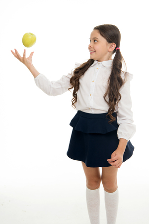 Child schoolgirl wear formal uniform hold apple. Girl cute pupil hold apple fruit stand on white background. Kid happy hold apple. School snack concept. Healthy nutrition diet. Apple vitamin snack.の写真素材