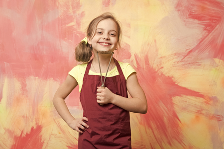 Childhood and education. Small girl on colorful background. Kid in cook apron. Chef child with masher for potato. Cooking with kitchen tool.の写真素材