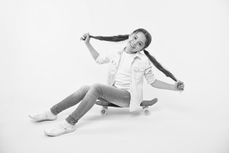 Girl show long ponytail hairstyle sit penny board yellow background. Child cute hairstyle ride penny board. Proud of long hair. Hairstyle for active leisure. Keep hairstyle tidy during sport activity.の写真素材