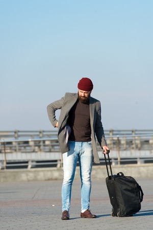Moving to new city alone. Traveler with suitcase arrive airport railway station urban background. Hipster ready enjoy travel. Carry travel bag. Man bearded hipster travel with luggage bag on wheels.の写真素材