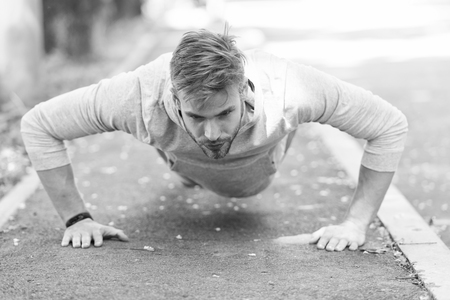 Strength and motivation. Man in sportswear doing push ups outdoor. Guy motivated workout in park. Sportsman improves his strength by push up exercise. Man has motivation to success sport achievement.の写真素材