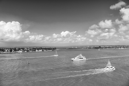 Yachts and sailboats in turquoise sea in key west, usa. Seascape with islands and boats on cloudy blue sky. Sailing and yachting. Summer vacation on tropical island. Sea adventure and trip.の写真素材