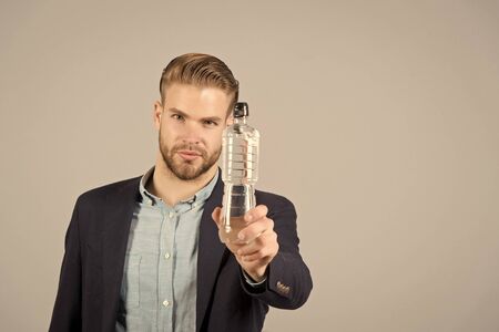 Man with plastic bottle on grey background, thirsty. Thirst, dehydration, drinking water concept. Health, diet, healthy lifestyle, copy spaceの写真素材