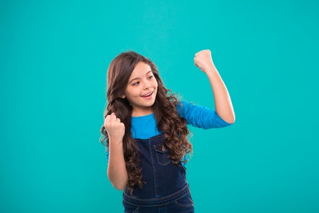 Achieve success. Kid cheerful celebrate victory. Girl cute child long curly hair happy smiling. Child psychology and development. Happy winner. Celebrate victory or achievement. Successful happy kid.の写真素材