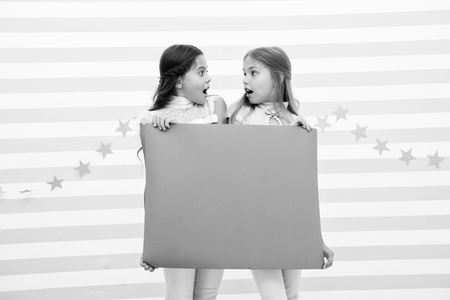 Shocking announcement concept. Amazing surprising news. Girl hold advertising banner. Girls kids holding paper banner for announcement. Shocked surprised children with blank paper copy space.の写真素材