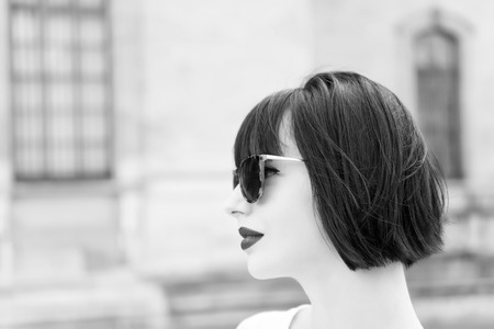 Girl fashionable lady with bob hairstyle outdoor urban architecture background. Woman fashionable model posing outdoor. Girl brunette bob hairstyle looks stylish. Hair styling tips from hairdresser.の写真素材