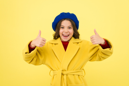 Child promoting something yellow background. Girl show thumbs up gesture. Advertising product. Look at this. Advertisement launching product. Advertisement concept. Place for ad advertisement.の写真素材