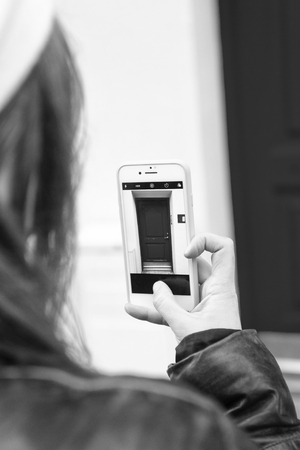 Someone taking mobile photo house entrance with red door. Daily photo shooting. Mobile app camera. Tourist photographer concept. App for shooting mobile phone photos high quality.の写真素材