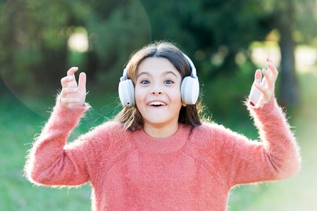 Listen in style. Little girl child wearing headphones. Happy child enjoy listening to music on the...