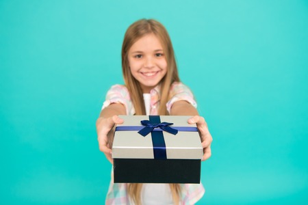 This is for you. Little shopaholic giving present wrapped in box. Small child with gift box tied with ribbon bow. Cute shopper enjoy doing a little shopping. Small girl after shopping for gift.の写真素材