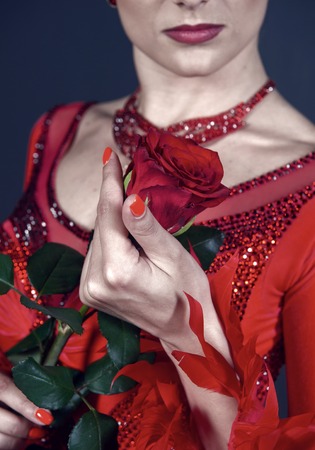 Rose flower in female hand on red dress. Love, desire, romance. Floristry, decor, design, floral shop. Womens day, 8 march spring Birthday anniversary holidays celebrationの写真素材
