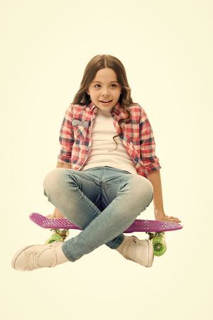 Sit and relax. Kid girl relaxed sits penny board. Learning how to ride penny board. Modern teen hobby. Girl happy face sit on penny board white background. Originally designed as girls skateboard.の写真素材