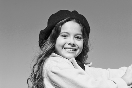 Girl walk blue sky background. Charming little french style fashionable girl. Hat accessory french fashion detail. Kid girl bright hat beret. Autumn hat fashion accessory. French trend fall season.の写真素材