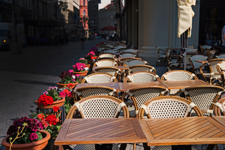 Tables, chairs and flowers in pots in sidewalk cafe on sunny day on streetscape background. Food service, catering, dining, lounge, entertainment conceptの写真素材