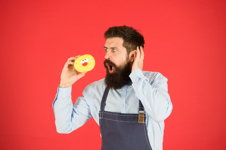 No way. True facts about sugar. Hipster bearded baker hold glazed donut on red background. Cafe and bakery concept. Sweet donut from baker. Man bearded baker in cooking apron hold cute dessert.の写真素材