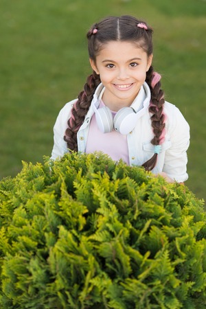 Secrets to raising happy child. Girl cute kid green grass background. Healthy emotional happy kid...
