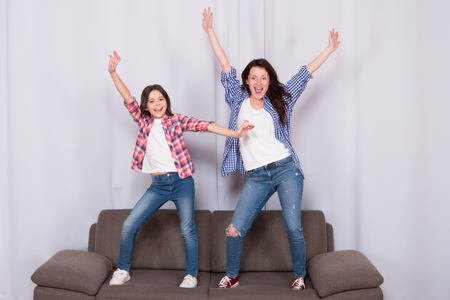 Going crazy together. Childrens day. mother and child at home. Family day. Little girl love her mother jump on sofa. Happy family. mother woman with daughter or sister. mothers day. sisterhood.の写真素材