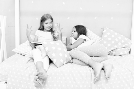Children read book in bed. Reading before bed can help sleep better at night. Stories every kid should read. Family tradition. Girls best friends read fairy tale before sleep. Best books for kids.の写真素材