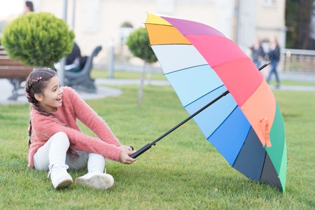 Colorful accessory for cheerful mood. Girl cheerful child long hair walking park with umbrella. Colorful accessory positive influence. Bright umbrella. Stay positive and optimistic. Optimistic child.の写真素材