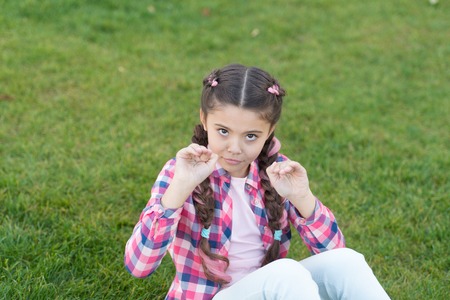 Springtime concept. Park and garden. Kid gadabout. Girl little kid spend leisure outdoors in park. Girl sit on grass in park. Child enjoy spring sunny weather while sitting at meadow in park.の写真素材