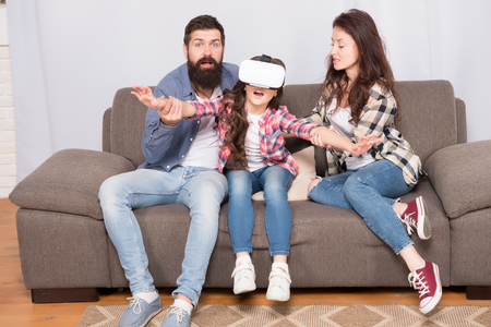 Lot of concern surrounding children using VR headsets. Daughter stuck in virtual reality. Digital world. Virtual life and dependence. Parents worry about kid in virtual reality. Virtual cyber gaming.の写真素材