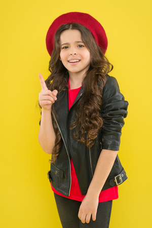 Be simply fashionable. Small girl in fashionable clothes pointing finger on yellow background. Little fashion model with fashionable look. Adorable child in fashionable modern styleの写真素材