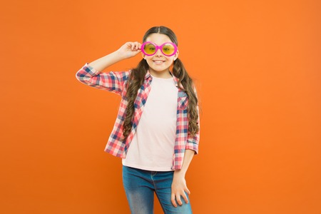 Look well and feel beautiful. Adorable girl with fashionable look on orange background. Little child having geeky look in fancy eyeglasses. Beauty look of small fashion modelの写真素材
