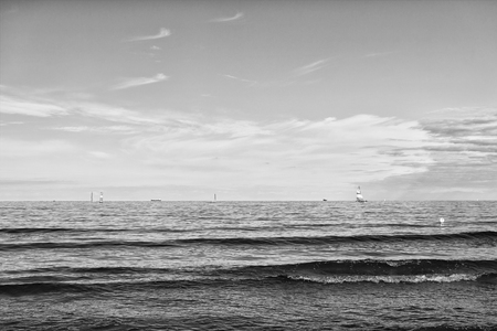 modern yacht or sailing boat or vessel sails by wind on sea water waves surface inshore on blue skyの写真素材