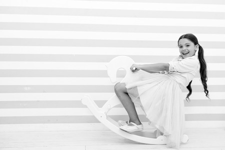 small kid fashion. International childrens day. Childhood happiness. small girl child with perfect hair. Happy little girl. Beauty and fashion. playful girl on toy pony. Loving her new style.の写真素材