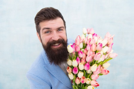 Spring holiday. Man bearded suit bow tie hold tulip flowers bouquet. Gentleman romantic surprise for her. Flowers delivery. Gentleman romantic date. Birthday greetings. Best flowers for girlfriend.の写真素材