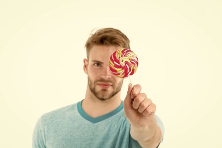 Man hold big sweet lollipop in front of his face. Man bearded likes sweets. Guy offers giant lollipop candy. Lollipop lick one of great oral techniques you can master. Would you like to lick lollipop.の写真素材