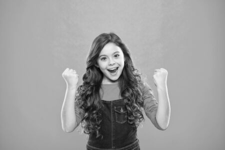 Kid cheerful celebrate victory. Girl cute child long curly hair happy smiling. Child psychology and development. Happy winner. Celebrate victory or achievement. Successful happy kid. Achieve success.の写真素材