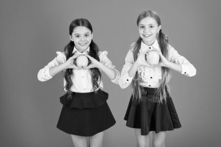 Cute schoolgirls holding apples.の写真素材