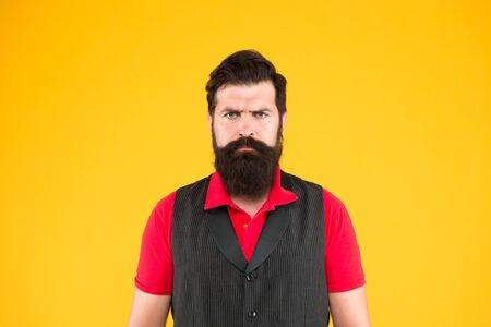 Hospitality staff. Restaurant cafe staff wanted. Man bearded hipster with mustache wear vest and shirt uniform yellow background. Shop staff concept. Salesman cashier career. Hiring shop store workerの写真素材