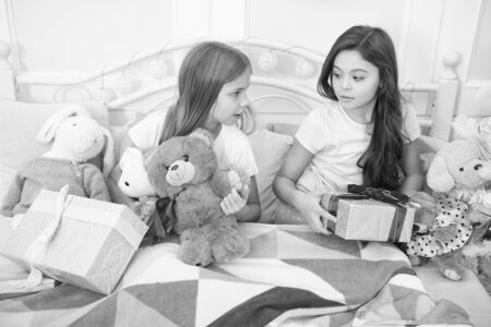 Merry Christmas and Happy New Year. Happy little children hold gift boxes. Little girls with presents in bed. Opening presents on Christmas morning. New Year surprise. Enjoy the moment to the fullestの写真素材