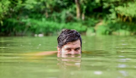 Man enjoy swimming in river or lake. Summer relax. Wild and free concept. Summer activity. Swimming sport. Freshness of wild nature. Summer vacation. Relaxation and rest. Refreshing feelingの写真素材