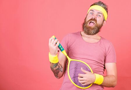 Man bearded hipster wear sport outfit. Having fun. Tennis active leisure. Athlete hipster hold tennis racket in hand red background. Tennis player vintage fashion. Tennis sport and entertainmentの写真素材