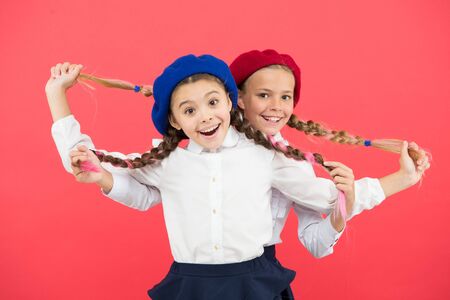 Exciting style. Happy small girls holding long plaited hair style on pink background. Little children smiling in french style. Giving school fashion a sense of styleの写真素材