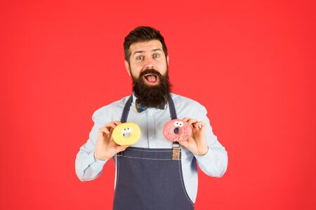 Junk food. Hipster bearded baker eat donuts. Doughnut bakery. Bearded cheerful well groomed man selling donuts. Carbs and calories. Bakery owner. Bakery business. Baked goods. Sweets and cakesの写真素材