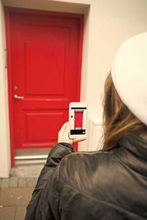 woman take a picture of red door on smartphone outside. digital age and facade design. photo of door on phone. navigation and locations. red point. this would be my home. i like it.の写真素材