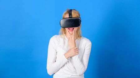 Pretty woman playing game in virtual reality glasses. Woman wearing virtual reality goggles in blue background. Excited smiling businesswoman wearing virtual reality glasses.の写真素材