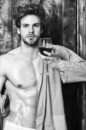 Bachelor enjoy wine. Macho tousled hair degustate luxury wine. Drink wine and relax. Erotic and desire concept. Guy attractive relaxing with alcohol drink. Man sexy chest sweaty skin hold wineglassの写真素材