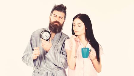 Girl with coffee cup, man holds clock in hand. Perfect morning concept. Couple, family woke up on...