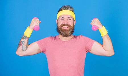 Man bearded athlete exercising dumbbell. Motivated athlete guy. Athlete on way to stronger body. Healthy habits. Sportsman retro outfit training blue background. Athlete training with little dumbbellの写真素材