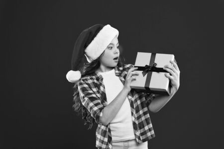 Waiting for wonder. Christmas shopping. New year party. Santa claus kid. Happy winter holidays. Small girl. Present for Xmas. Childhood. Little girl child in santa red hatの写真素材