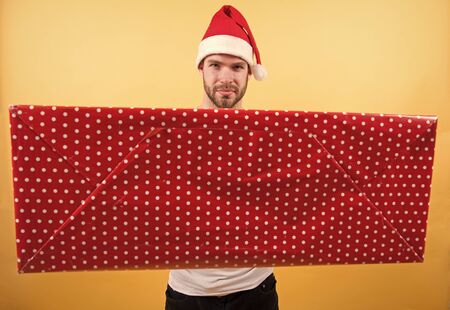Man handsome unshaven santa hat hold gift boxの写真素材