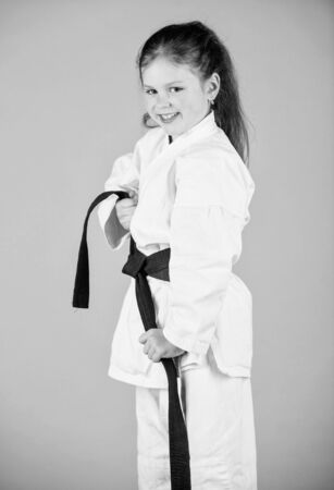 small girl in martial arts uniform. little girl in gi sportswear. practicing Kung Fu. happy childhood. knockout. energy and activity for kids. sport success in single combat. Having a little breakの写真素材